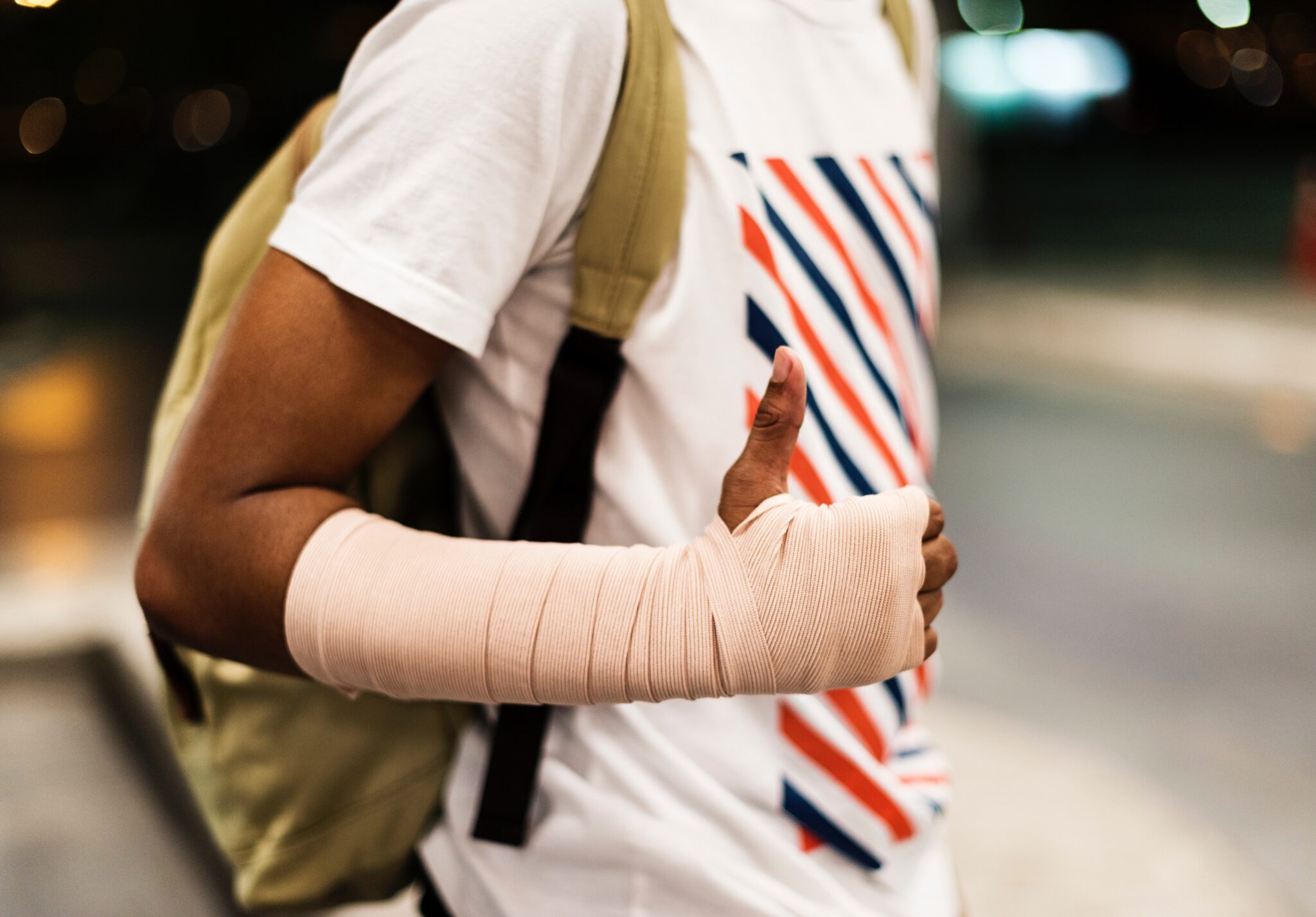 young man with arm bandage giving thumbs up