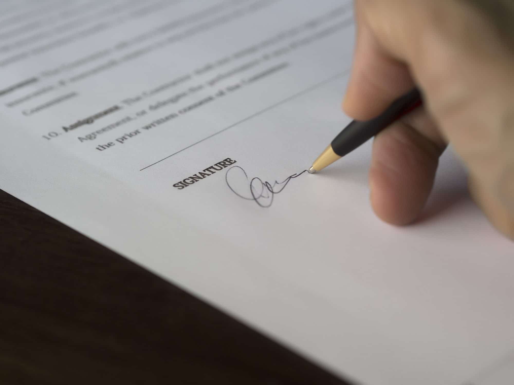 person signing document with pen