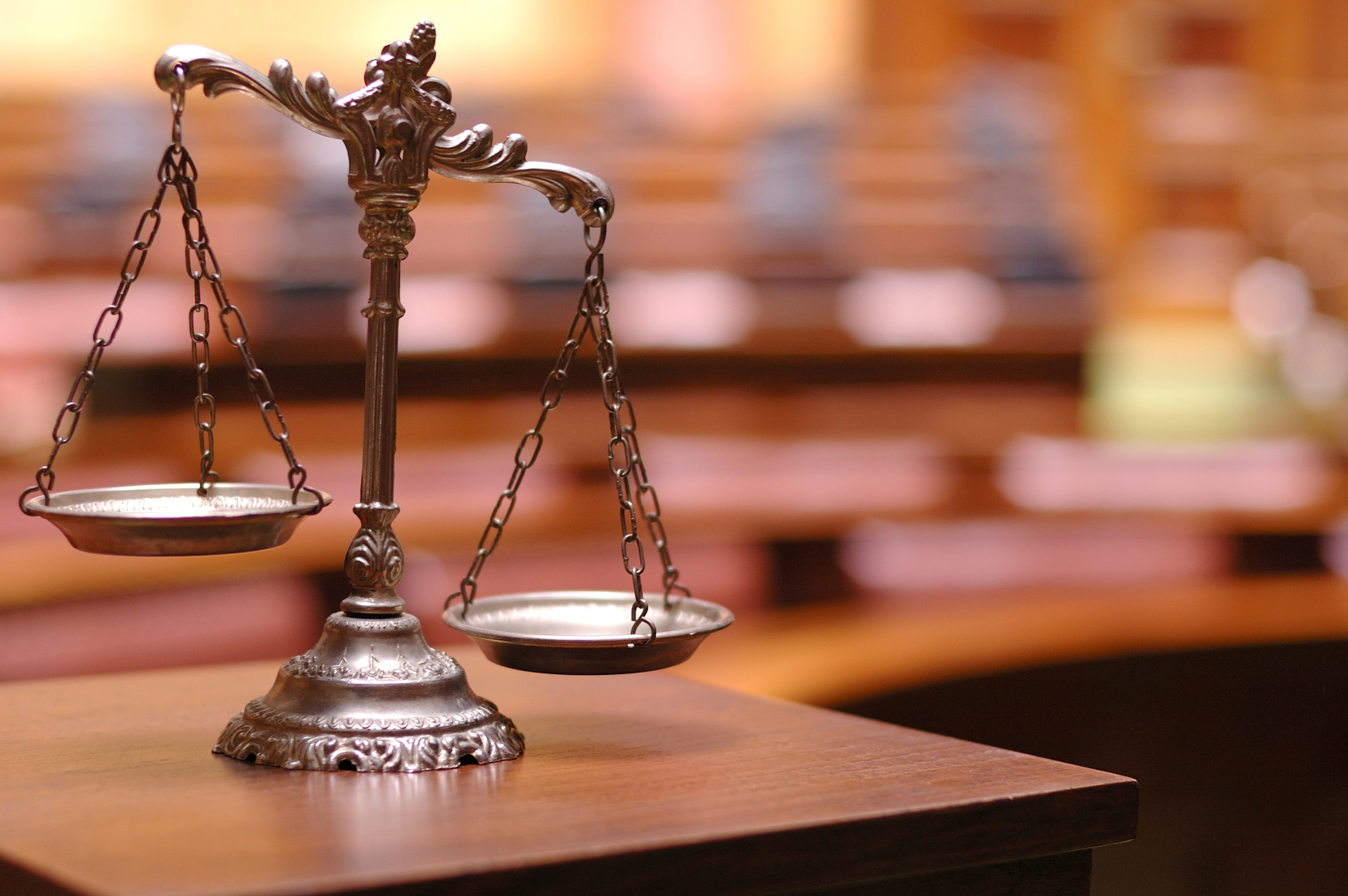 scales of justice against blurred background of courtroom