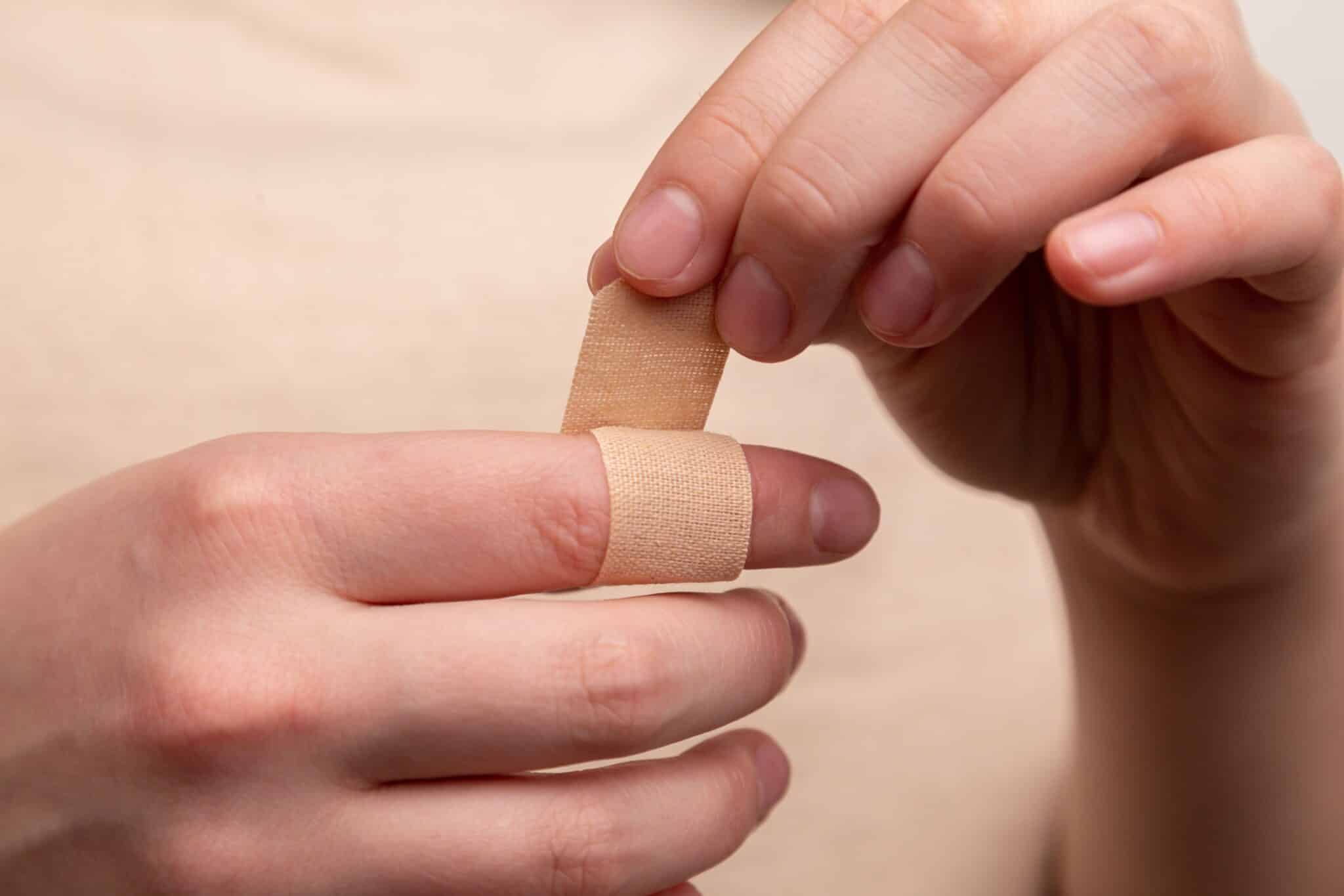closeup of woman applying bandaid to her finger