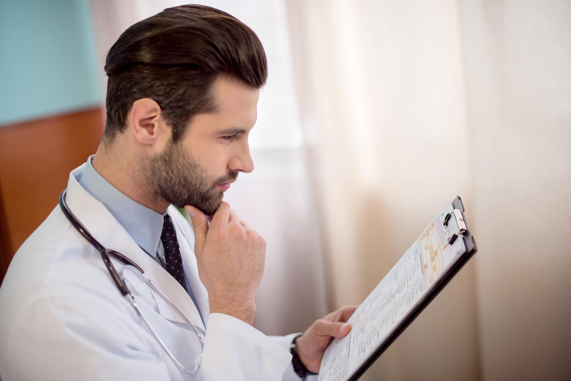 doctor looking intently at medical chart on clipboard