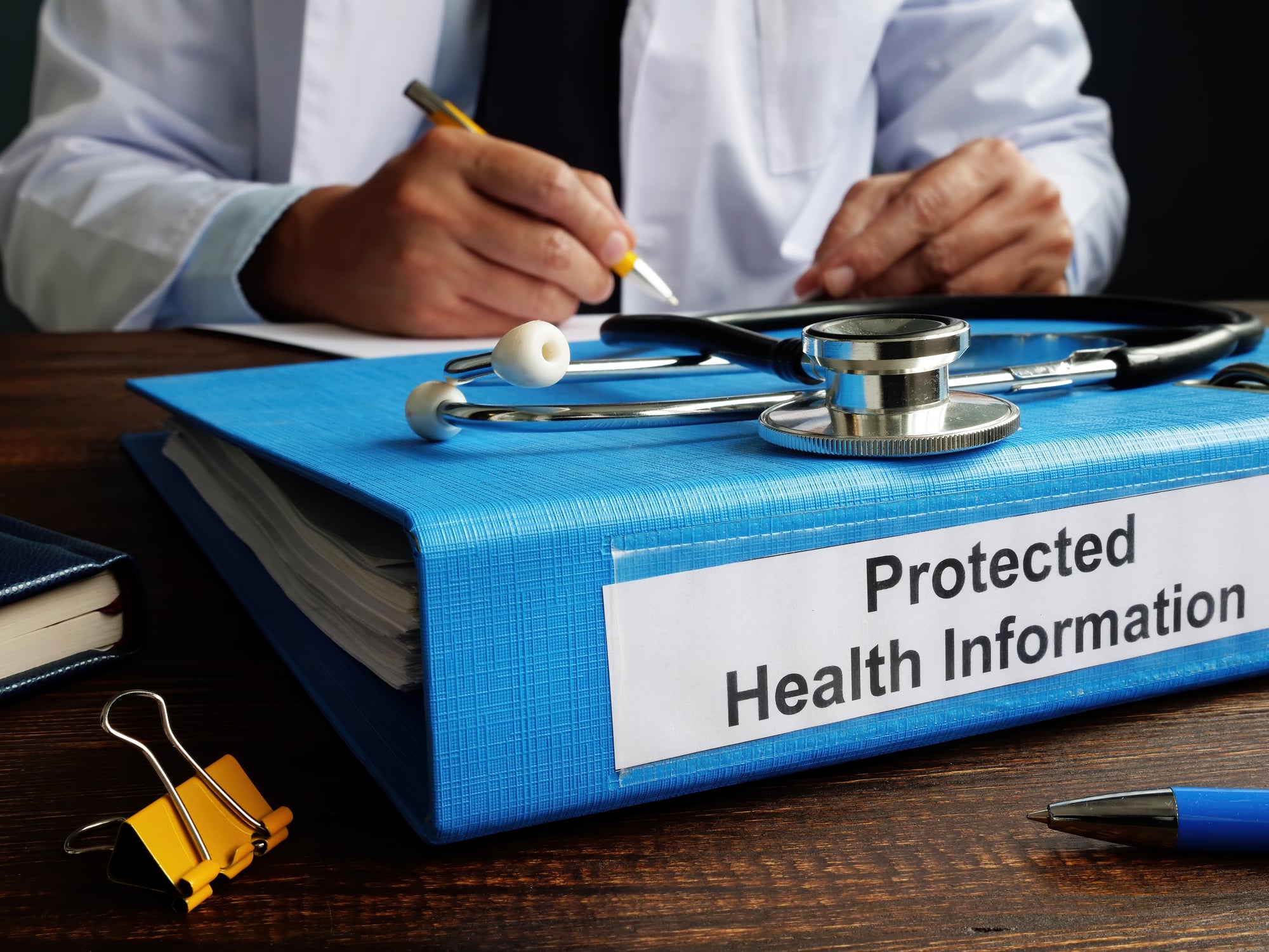 doctor with large binder labeled "Protected Health Information"